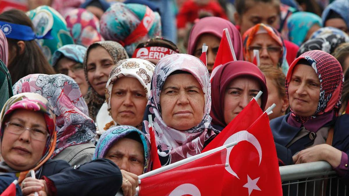 FILE - In this May 30, 2015, file photo, supporters of Turkey's president, Recep Tayyip Erdogan, and prime minister and leader of the Justice and Development Party (AKP), Ahmet Davutoglu, some holding Turkish flags, wait for their appearance in Istanbul during a rally to commemorate the anniversary of city's conquest by the Ottoman Turks. As extremist violence and political uncertainty cast a shadow over Turkey, voters are looking for the parliamentary election to usher in stability. (AP Photo/Lefteris Pitarakis file)